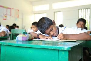 Middle school boy writing in class at Trinity College Kandy