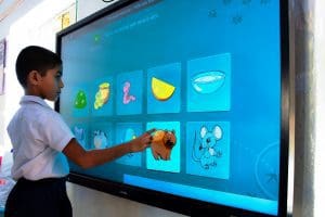 A Kindergaren student playing an educational game on a smartboard